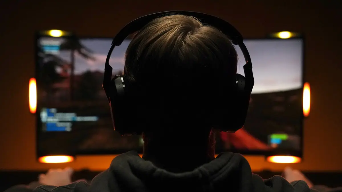 Player wearing a headset facing a monitor with glowing light bars